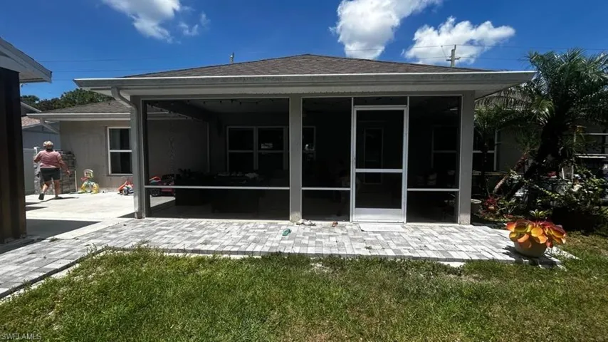 Screened-in patio with light-toned paver flooring, featuring a white-framed screen door and ample space