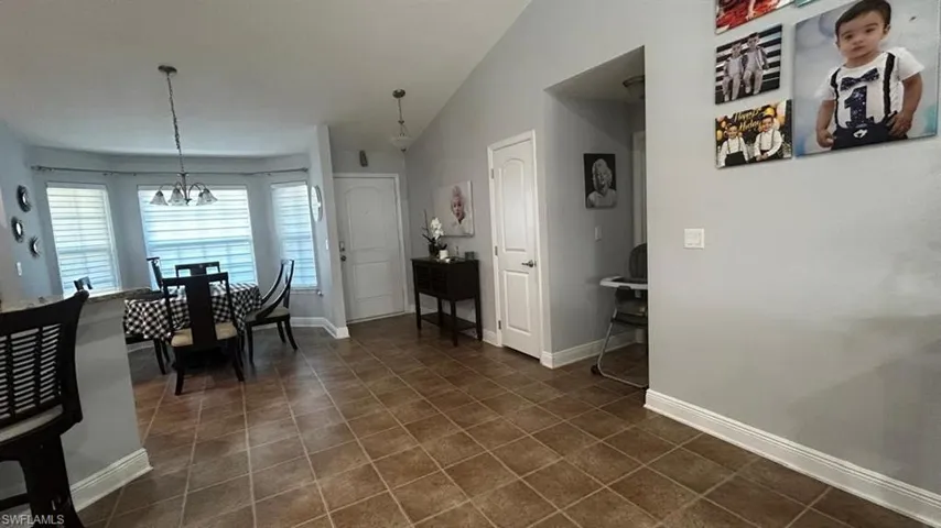 Tiled flooring extending into dining area with bay windows and a chandelier