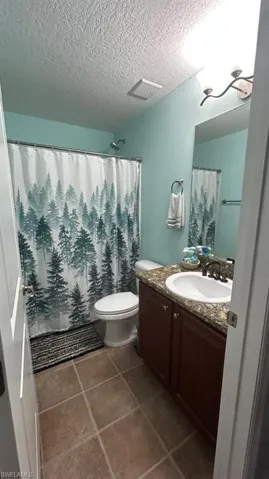 Bathroom featuring a dark wood-finish vanity with an undermount sink, a flecked countertop, and an expansive mirror