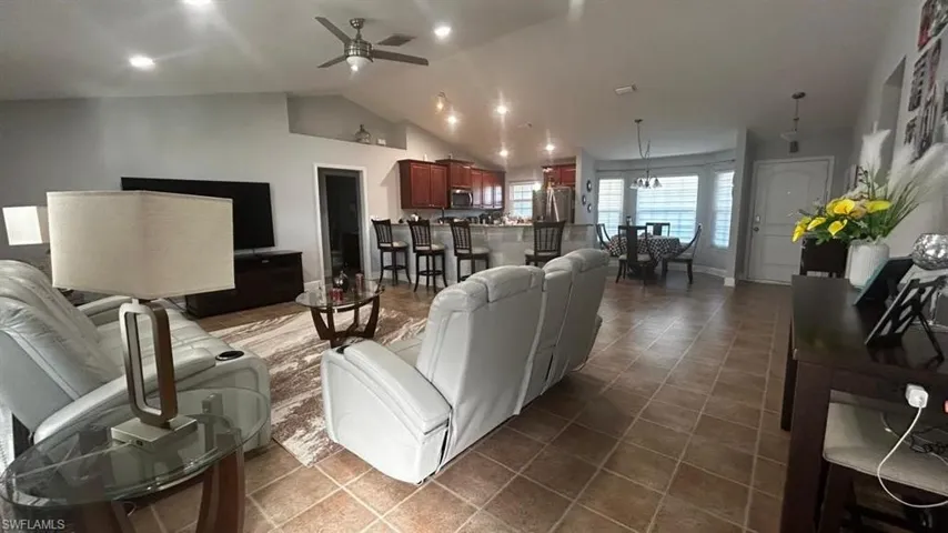 Open-concept living space featuring vaulted ceilings, recessed lighting, and tile flooring