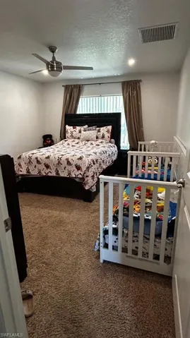 Carpeted room featuring a ceiling fan with integrated lighting, recessed lighting, and a window with blinds and drapes