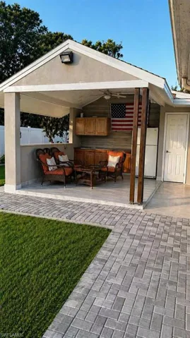 Covered outdoor living space featuring an integrated outdoor kitchen with wood cabinetry