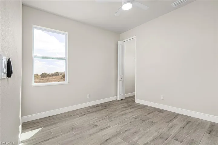 Unfurnished room with ceiling fan, a wealth of natural light, and light wood-type flooring