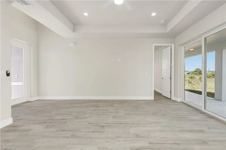 Spare room with light hardwood / wood-style flooring, a tray ceiling, and ceiling fan