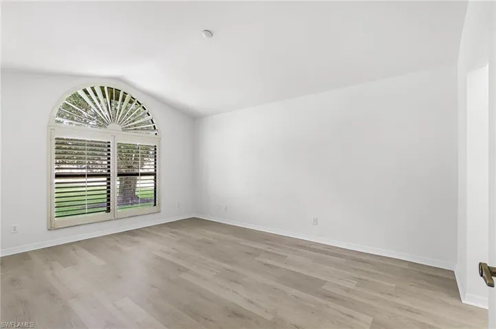 Unfurnished room with vaulted ceiling and light wood-type flooring