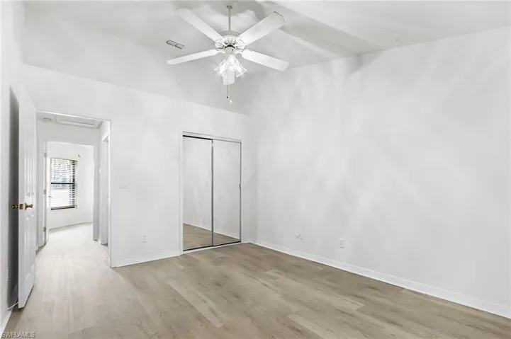 Unfurnished bedroom with light wood-style flooring, a closet, and a ceiling fan