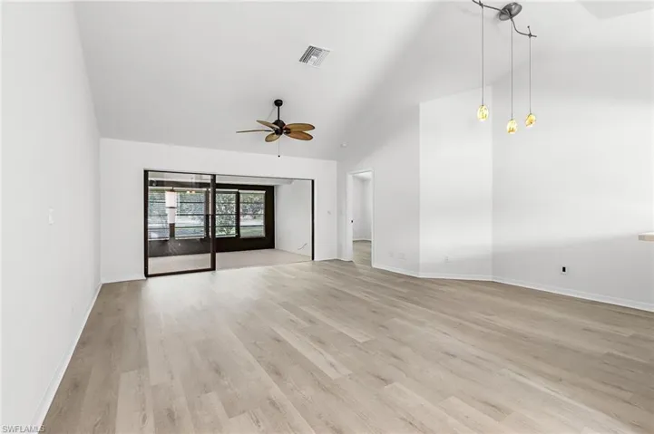 Unfurnished living room with high vaulted ceiling, light wood-style floors, and a ceiling fan