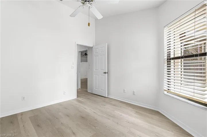 Unfurnished bedroom with light wood-type flooring, a ceiling fan, and a high ceiling