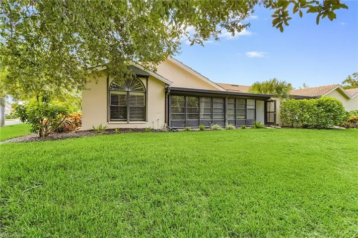 Rear view of house featuring stucco siding and a yard