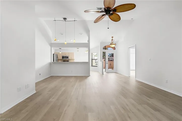 Unfurnished living room with light wood-style flooring, high vaulted ceiling, and a ceiling fan