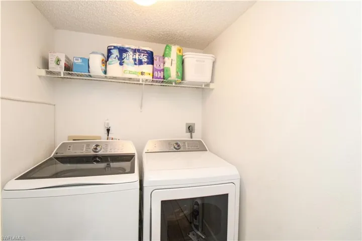 Washroom with a textured ceiling and washing machine and clothes dryer