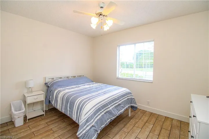 Bedroom with ceiling fan, a textured ceiling, and light wood-type flooring