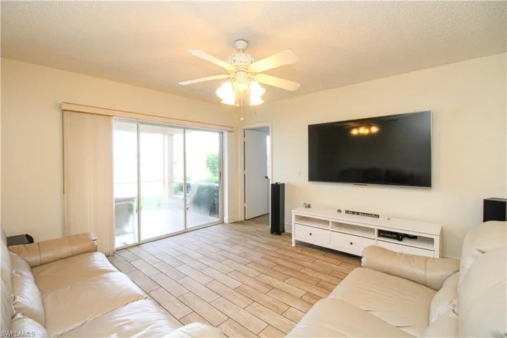 Living room with ceiling fan, a textured ceiling, and light hardwood / wood-style flooring