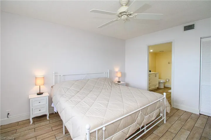 Bedroom featuring wood-type flooring, a closet, connected bathroom, and ceiling fan