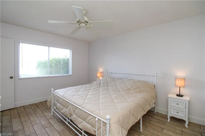 Bedroom with wood-type flooring, ceiling fan, and a textured ceiling