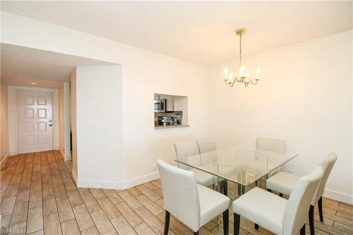 Dining space featuring a textured ceiling, an inviting chandelier, and light hardwood / wood-style flooring