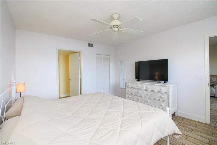 Bedroom featuring light wood-type flooring, a textured ceiling, ceiling fan, and a closet