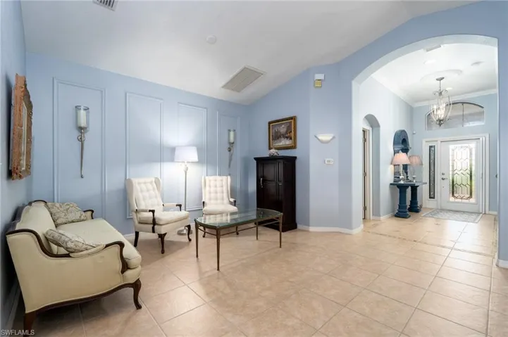 Sitting room with light tile patterned floors, a chandelier, lofted ceiling, and ornamental molding