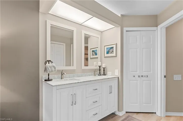 Full bath with wood finished floors, a sink, baseboards, a closet, and double vanity