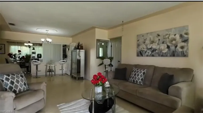 Open-concept living area featuring a neutral color palette, crown molding, and light-toned flooring