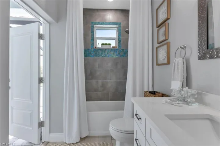 Full bathroom with shower / bathtub combination with curtain, vanity, and toilet