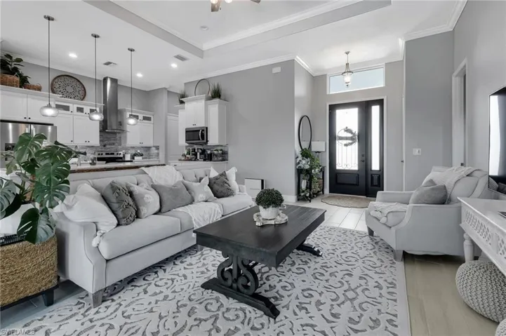 Living room with crown molding, a towering ceiling, ceiling fan, and light wood-type flooring