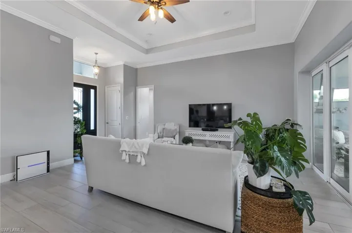 Living room featuring crown molding, ceiling fan, and a tray ceiling