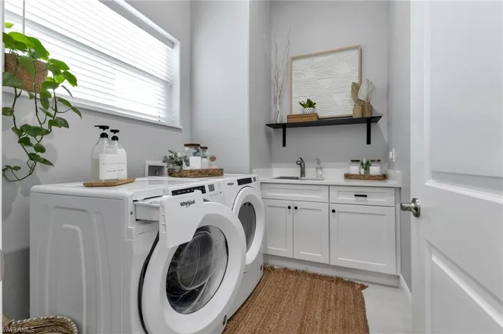 Clothes washing area featuring sink, cabinets, and independent washer and dryer