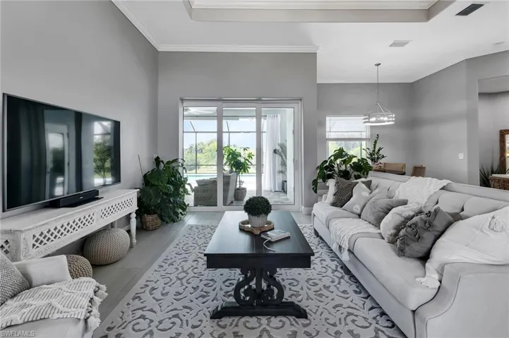Living room featuring crown molding, light hardwood / wood-style floors, and a notable chandelier