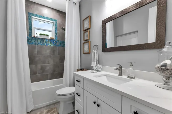 Full bathroom featuring vanity, shower / bathtub combination with curtain, tile patterned floors, and toilet