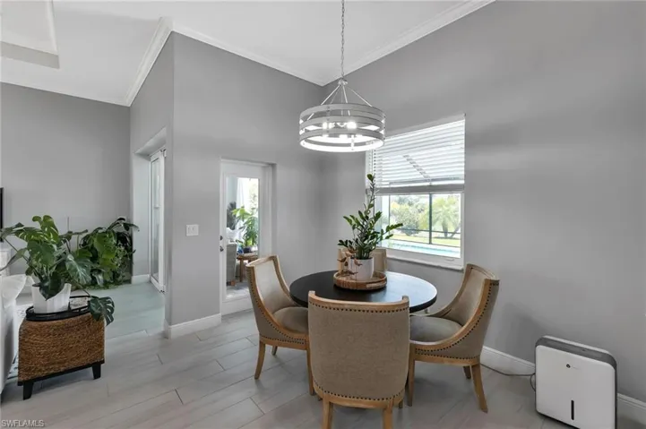 Dining area with a notable chandelier, ornamental molding, and light hardwood / wood-style floors
