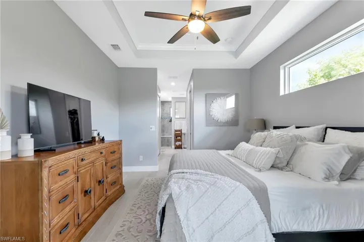 Bedroom featuring ceiling fan, a tray ceiling, and light hardwood / wood-style floors