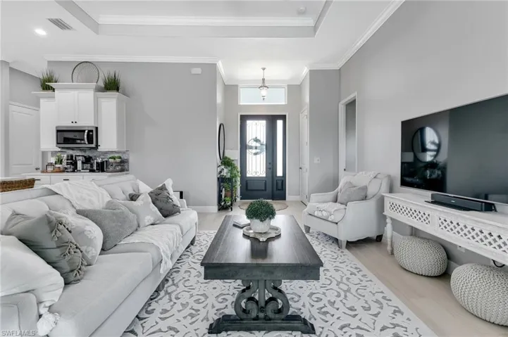 Living room featuring ornamental molding, a tray ceiling, and light hardwood / wood-style floors