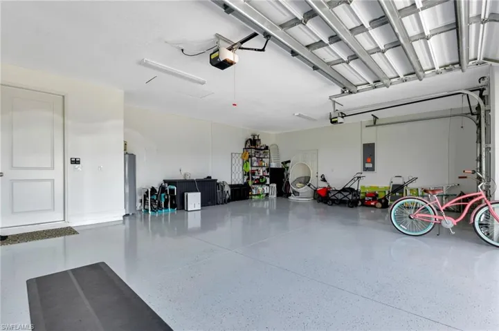 Garage with a garage door opener, electric panel, and water heater
