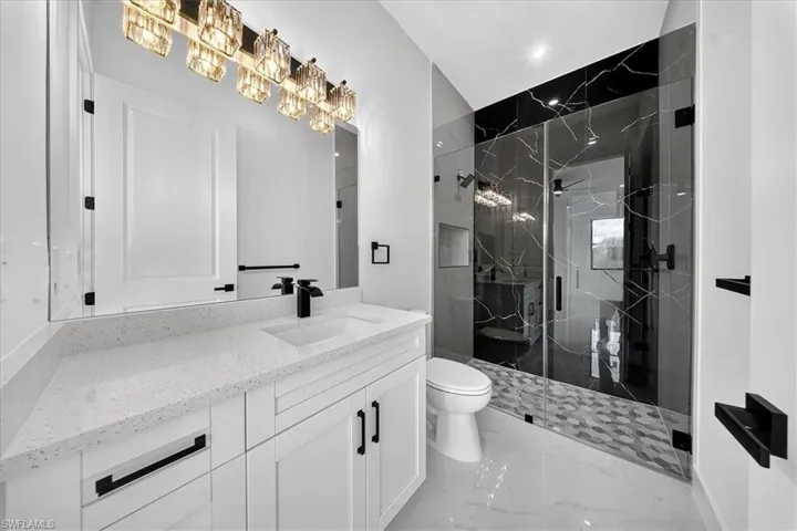 Full bath with vanity, a marble finish shower, and light marble finish flooring