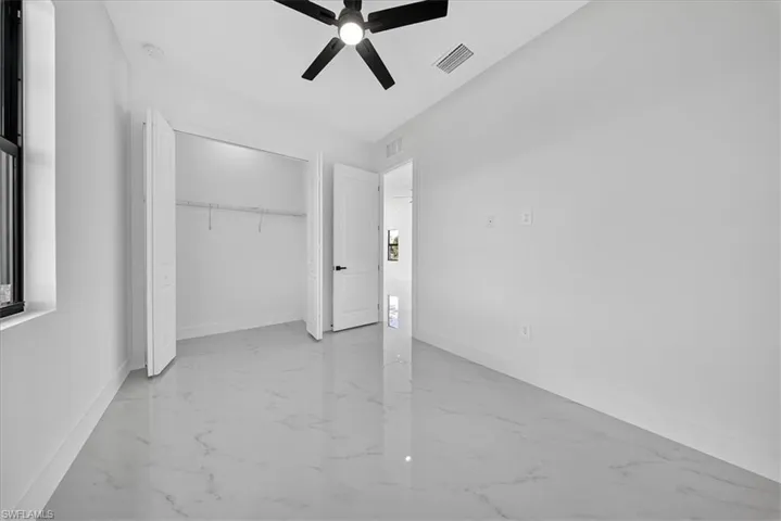 Unfurnished bedroom featuring a ceiling fan, a closet, and light marble finish floors