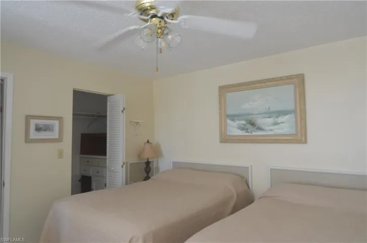 Bedroom featuring ceiling fan, a walk in closet, a textured ceiling, and a closet