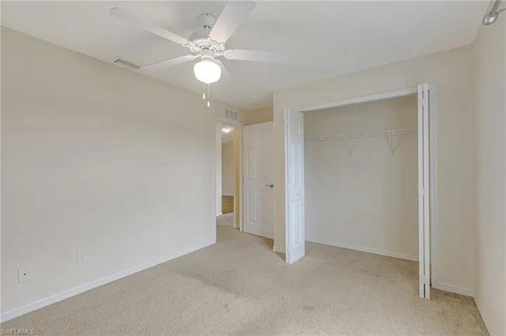 Bedroom with light colored carpet, a closet, and ceiling fan