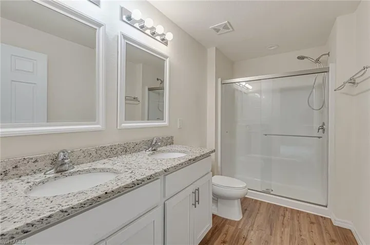 Comfort and style combined in this bathroom with shower, laminate floors, and double vanities