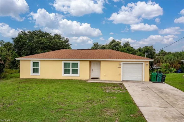 Single story home with large front yard, driveway, and an attached 1-car garage
