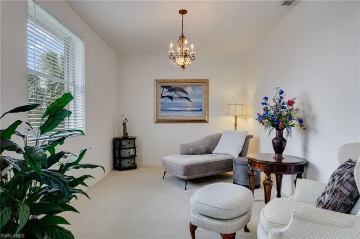 Sitting room with suspended lighting and carpet floors