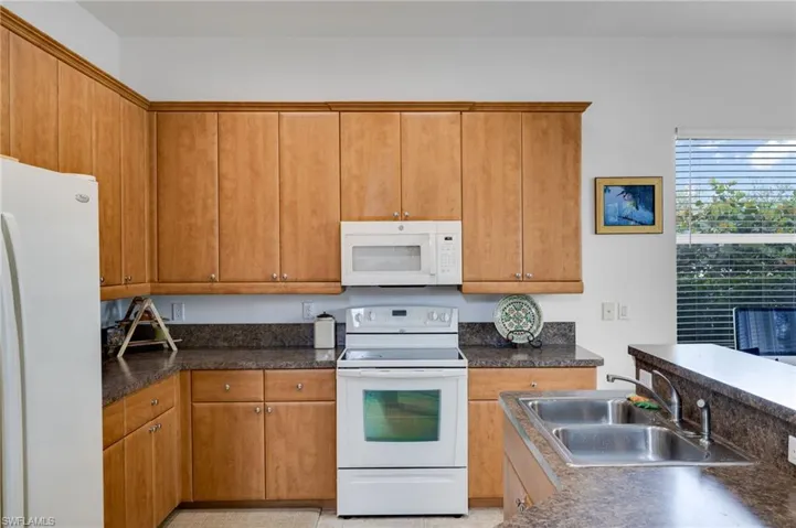 Kitchen featuring white appliances, dark countertops, and wood finish cabinetry