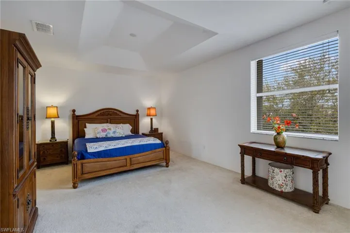 Bedroom with light colored carpet and a raised ceiling