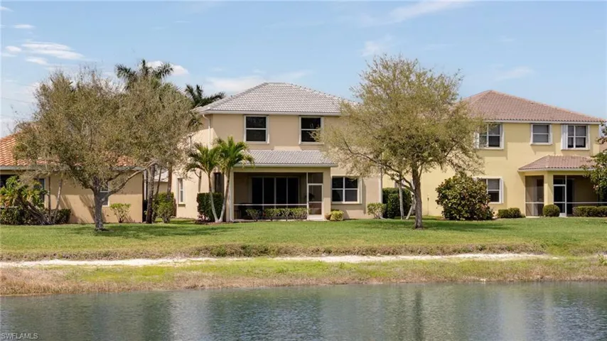 Back of property with a tiled roof, stucco siding, a sunroom, and a water view