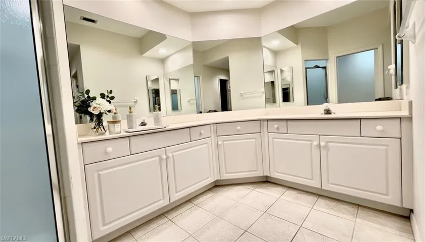Full bath with double vanity and light tile patterned floors