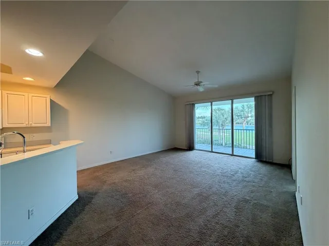 Unfurnished living room featuring dark carpet, vaulted ceiling, recessed lighting, and a ceiling fan