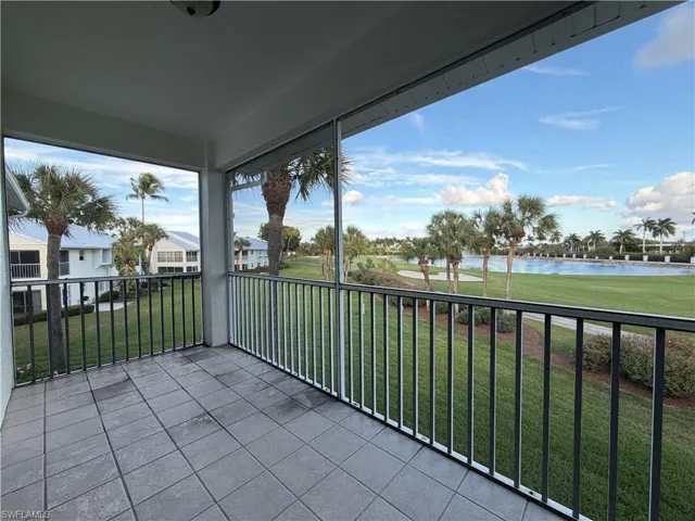Balcony with a water view, view of golf course, and a sunroom