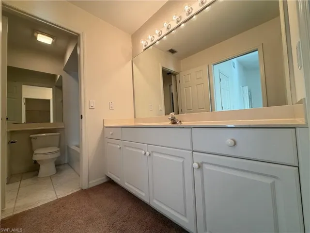 Bathroom with vanity, dark carpet, bathing tub / shower combination, and dark tile patterned floors