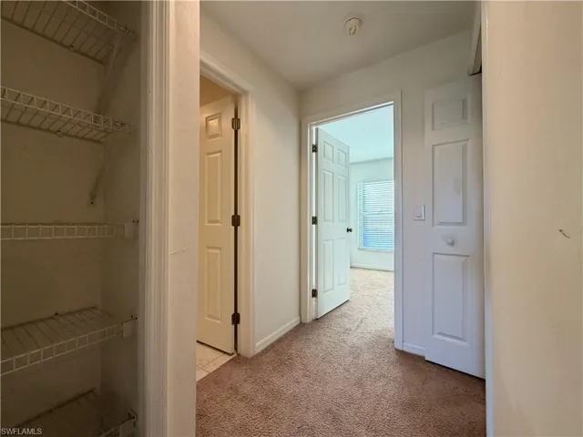 Corridor with light colored carpet and baseboards
