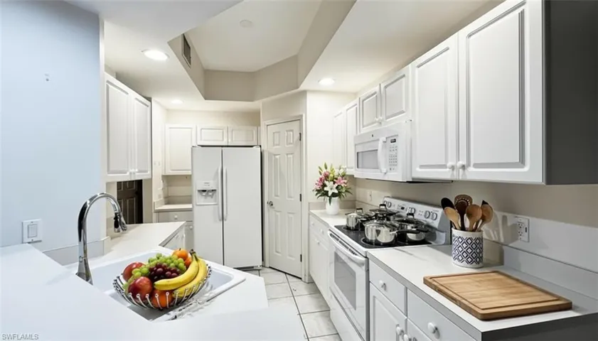Kitchen with white appliances, white cabinetry, light countertops, recessed lighting, and light tile patterned floors
